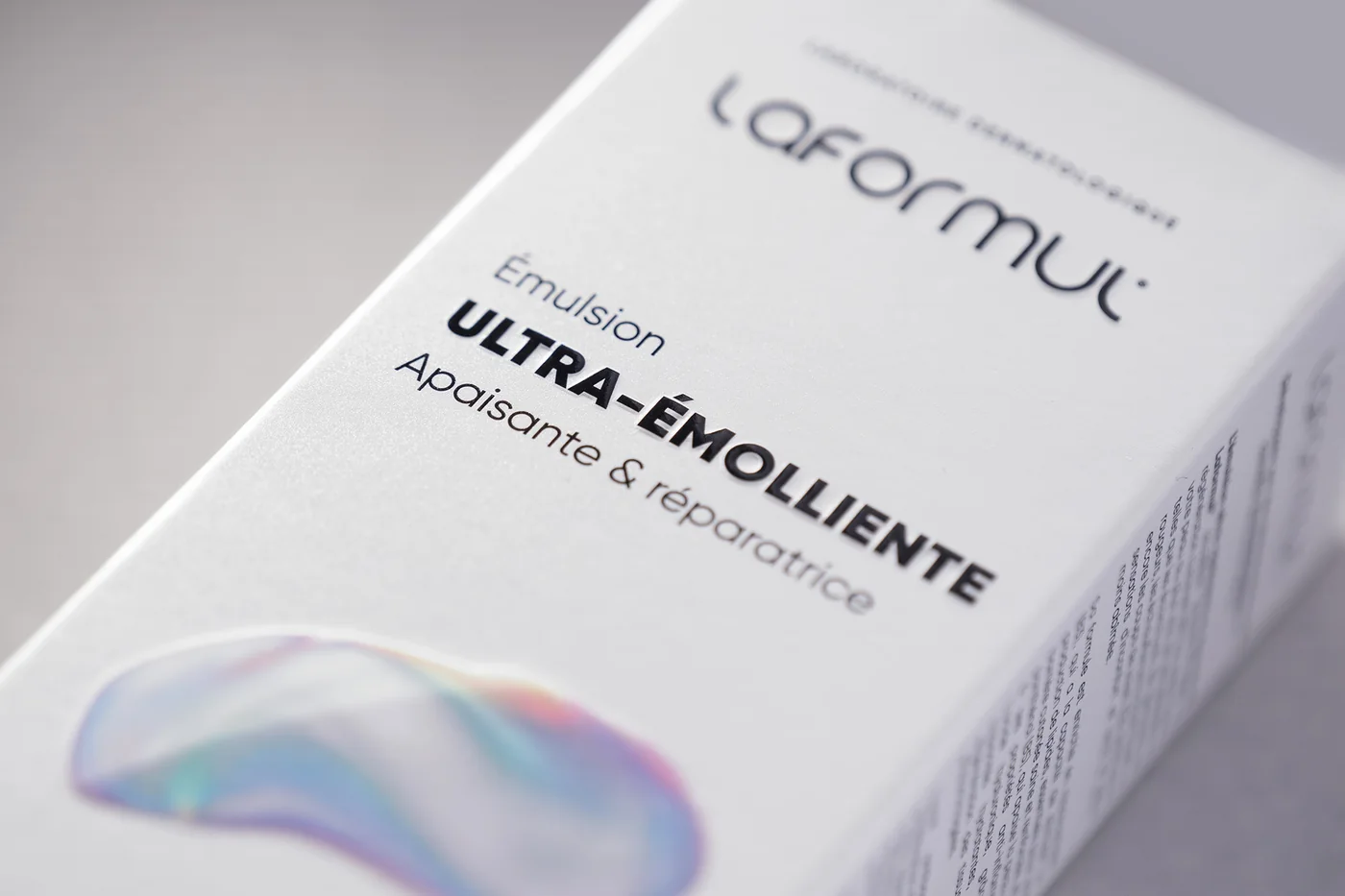 The Laformul Émulsion Ultra-Émolliente carton, close up, the product name embossed in black on pearl board