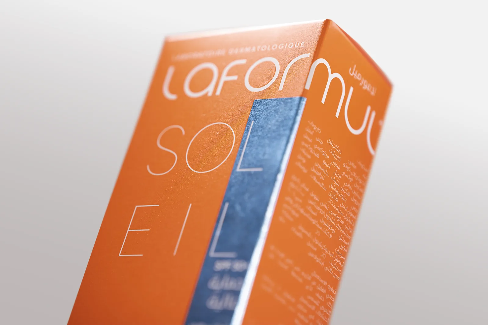 The Laformul Soleil carton, close up: the wordmark reversed out of orange beside a reflective blue band